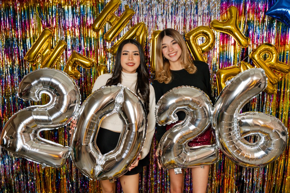 Dos amigas sosteniendo los globos plateados del 2026