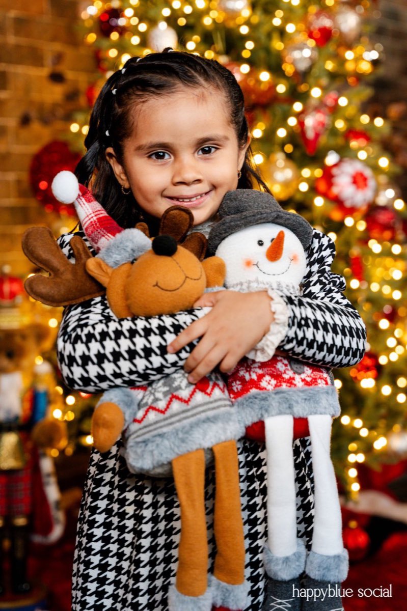Una niña abrazando un reno y un muñeco de nieve de peluche