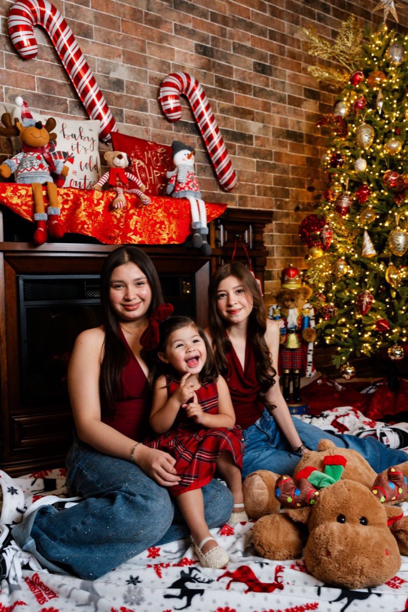 Tres hermanas sentadas junto al árbol, la más chica riéndose