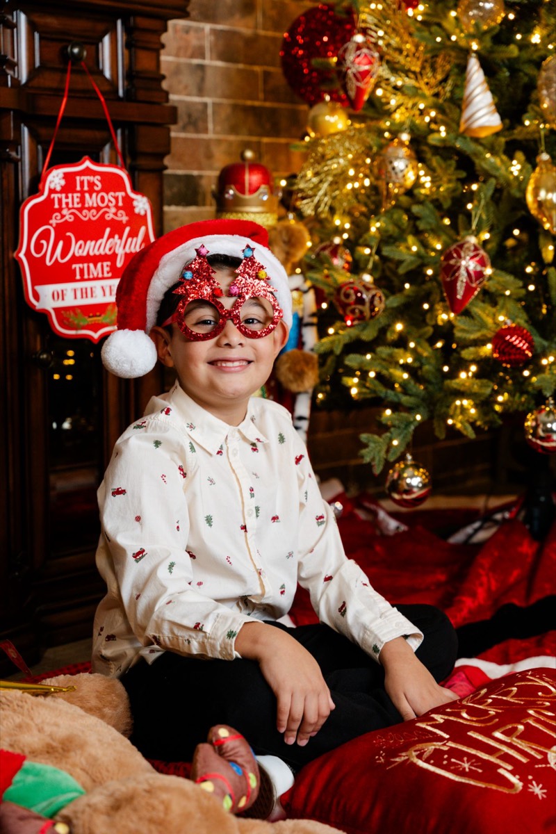 Un niño con gorro de Santa y lentes rojos de arbolitos