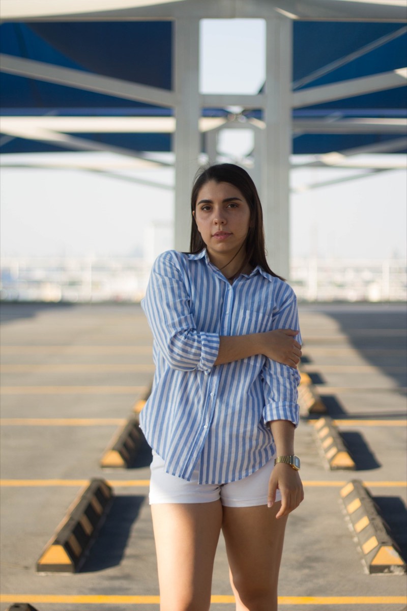 Una modelo de camisa de rayas azules en una azotea, con la ciudad detrás