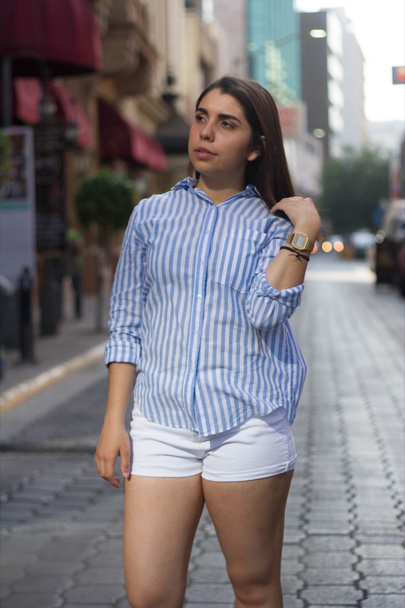 Una modelo de camisa de rayas azules caminando por una calle del centro de Monterrey